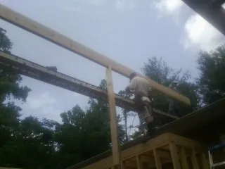 Carpenter setting a ridge beam over a new addition frame — Ice Dam Removal by Roofing Brothers in Vernon Center