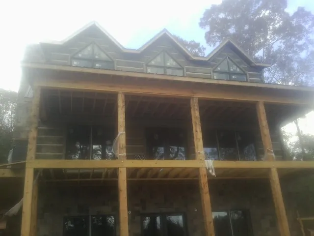 Dormers and porch framing on a large log home under construction — Roof Coating work by our crew in Vernon Center