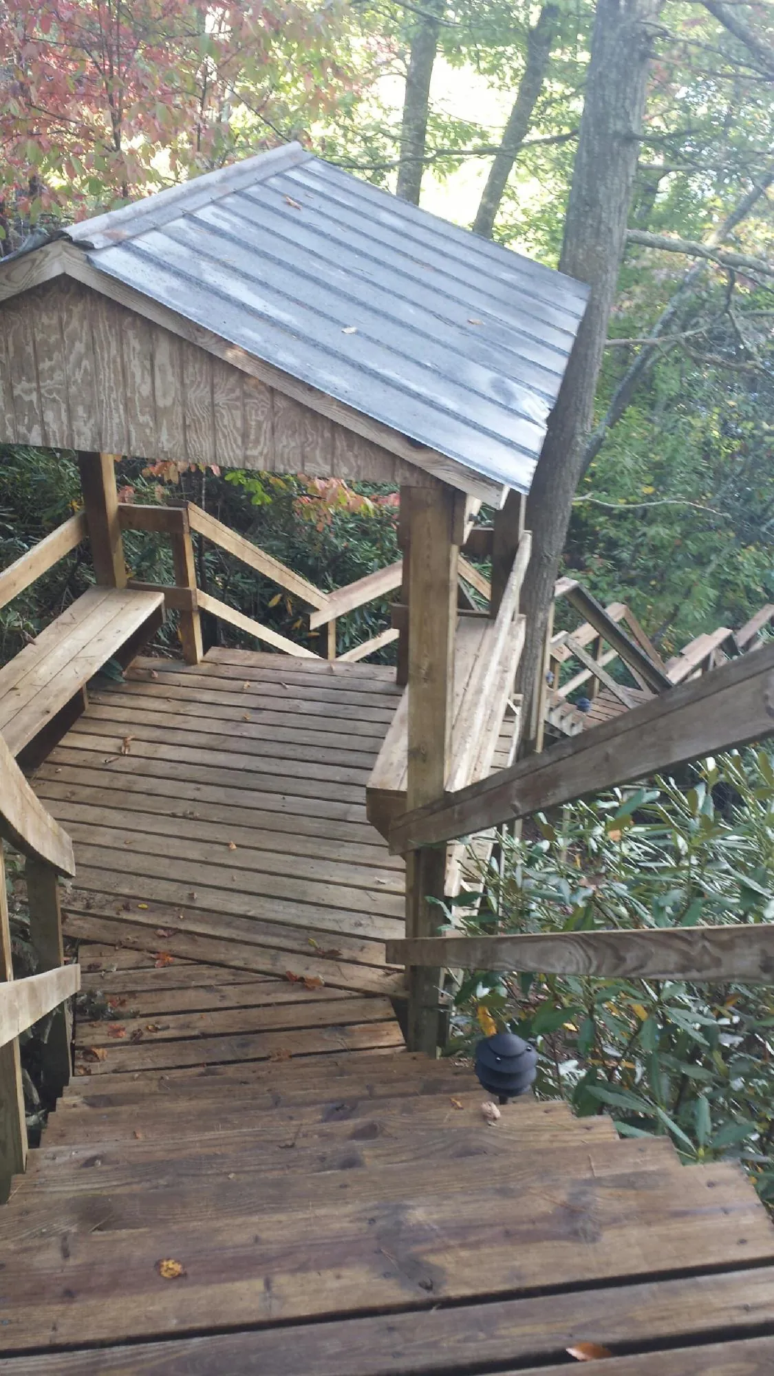 Metal roofed shelter over wooden steps on a wooded walkway — Skylight Repair & Installation work by our crew in Vernon Center