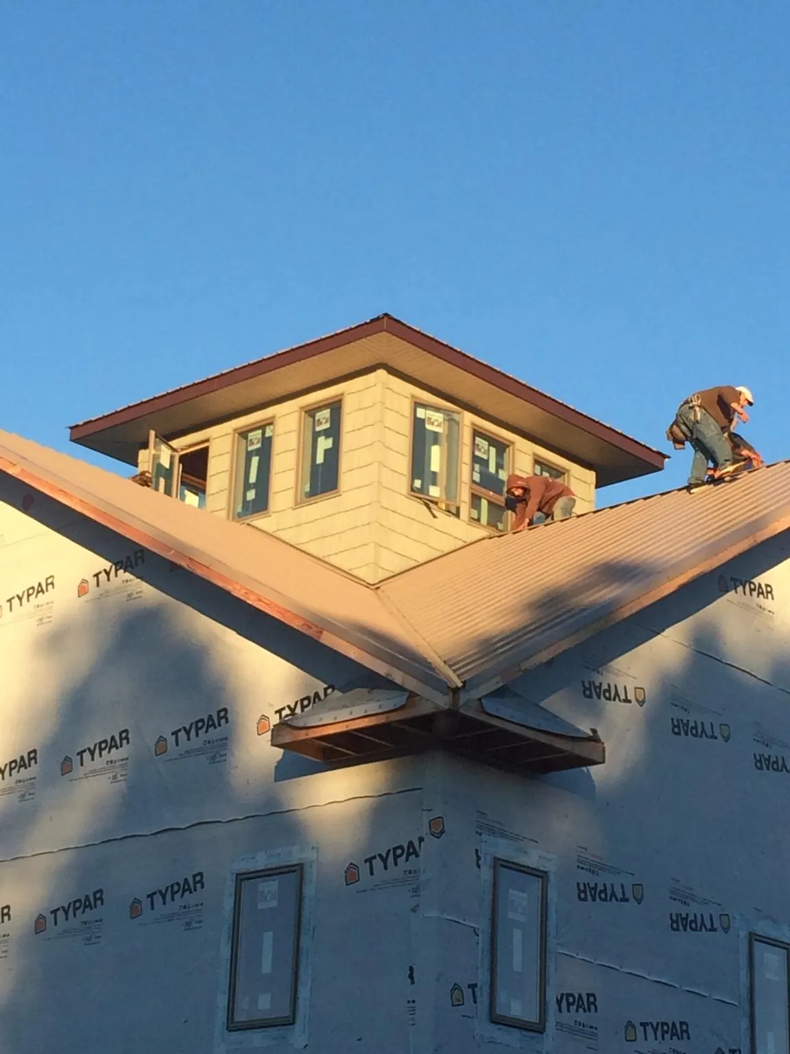 Roofers working around a rooftop cupola on a new metal roof at sunset — Roof Waterproofing in Vernon Center by Roofing Brothers